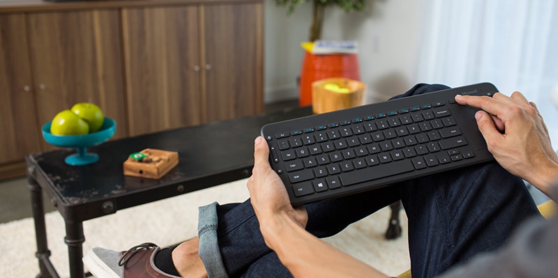 Person using the Microsoft All in One Keyboard in a living room. 
