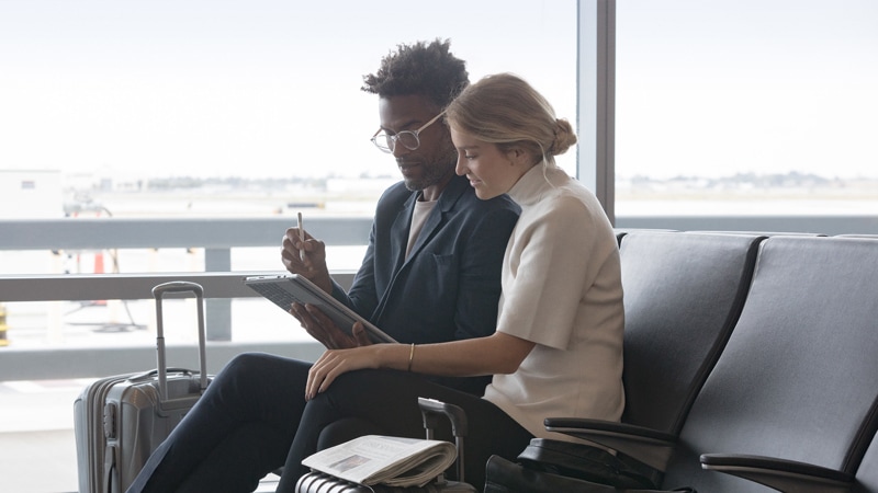 A man and a woman work with Surface Pen on a Surface Pro in an airport waiting area