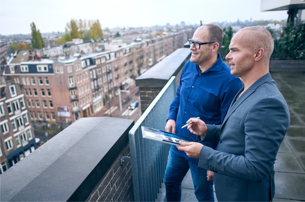 Two men on an office balcony with a Windows 10 PC.
