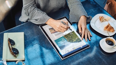 A person using a digital pen to edit a document on a new Windows 10 computer.
