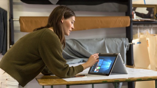 Mulher em pÃ interagindo com seu PC com Windows 10 em uma mesa no escritÃrio.
