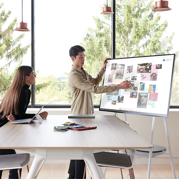 Photograph of people collaborating in front of a Surface Hub electronic whiteboard.