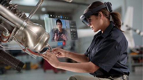 A woman wearing a HoloLens 2 headset works on a piece of machinery.