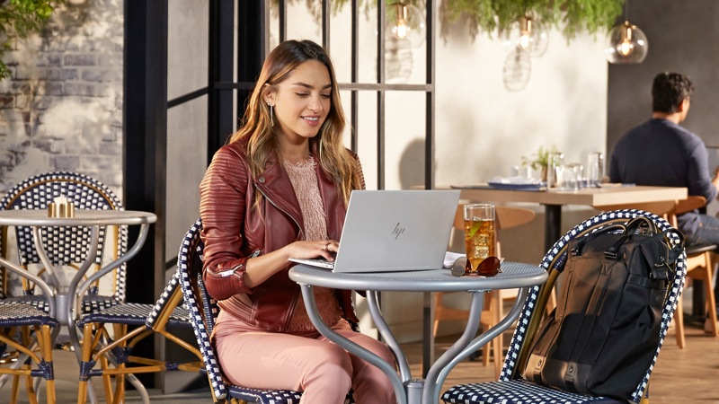 Woman using HP Envy 13 laptop at table in cafe