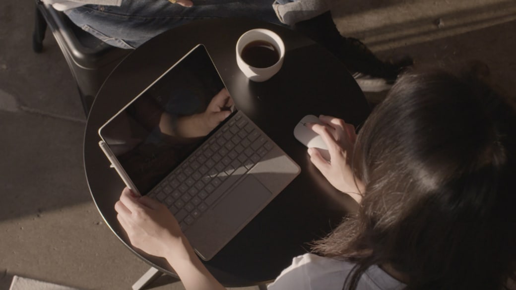 Una mujer trabaja en un Surface Go en un café