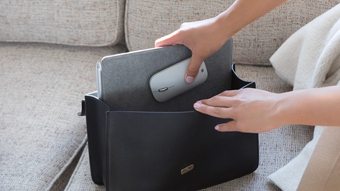 A woman puts Surface Lingo and Surface Mobile Mouse in her purse