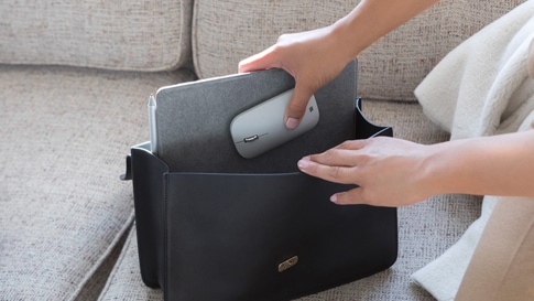 Eine Frau verstaut Surface Lingo und Surface Mobile Mouse in Ihre Tasche