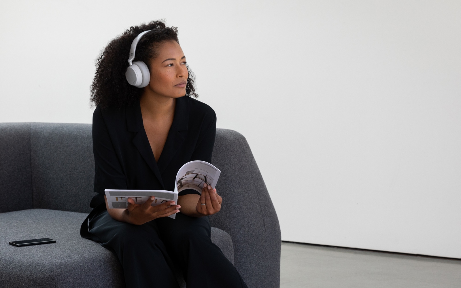Surface Headphones で、ソファに座って音楽を聴く女性