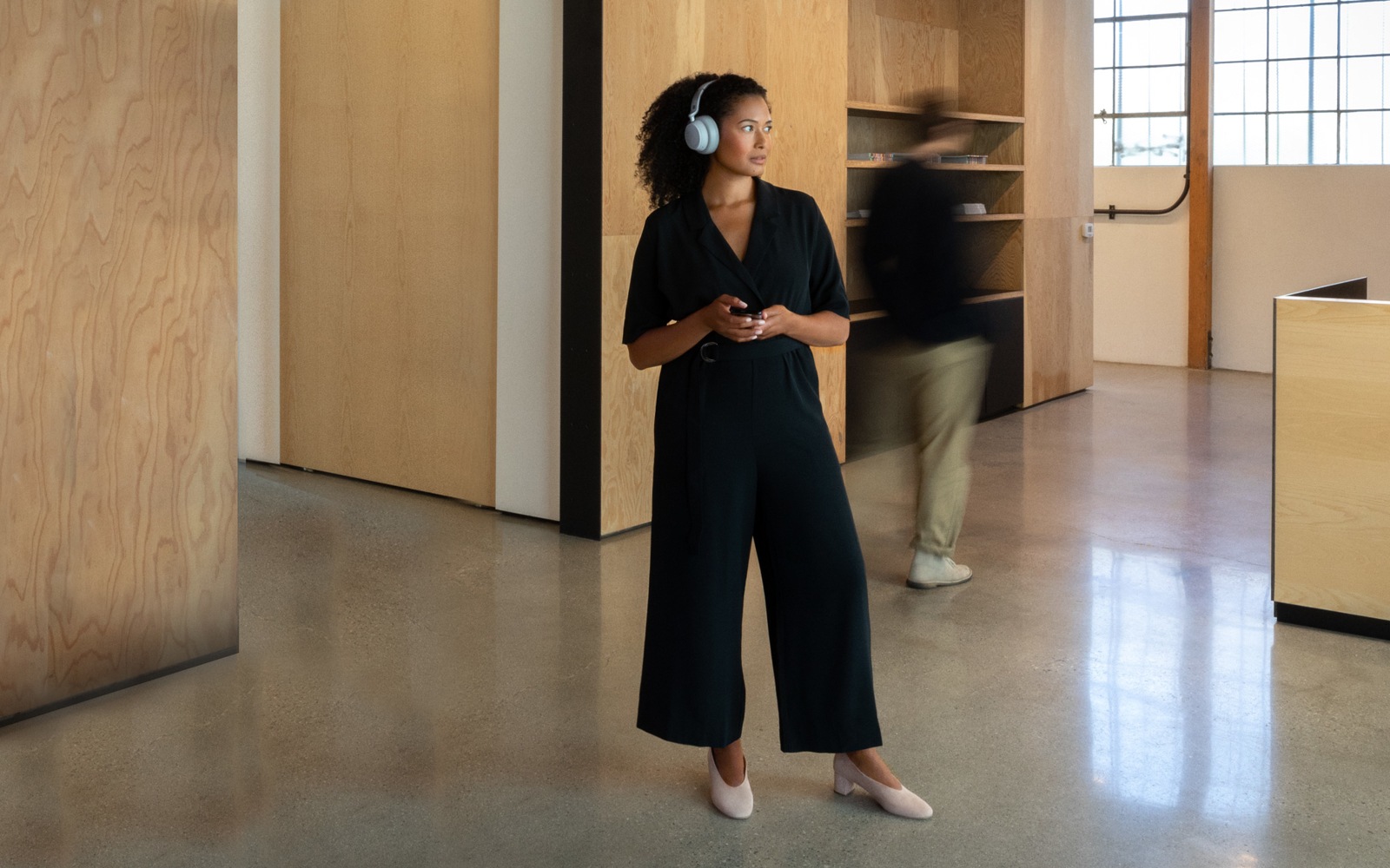 A woman standing with Surface Headphones on her head