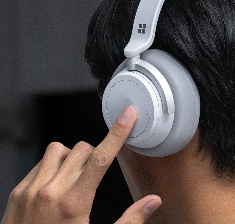 A man touching the left side and dial on Surface Headphones