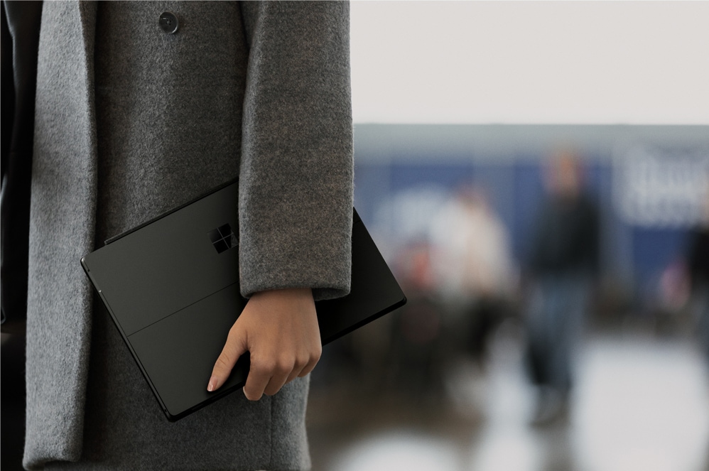 Woman holding Black Surface Pro 6 with black wool coat on