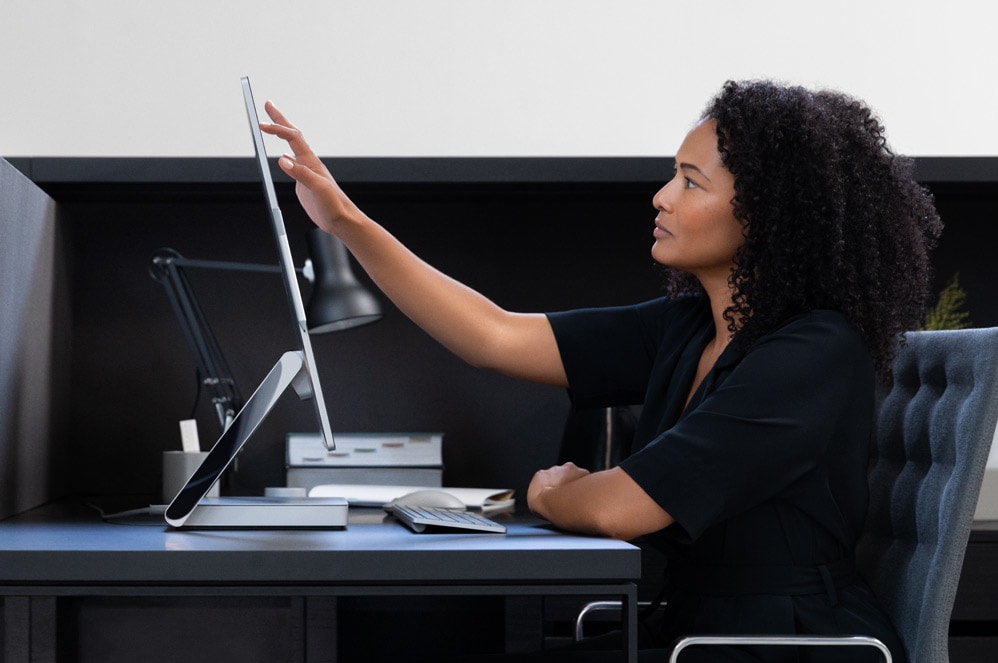 En kvinna tar på skärmen på en Surface Studio 2