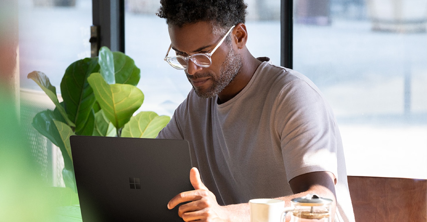 Photograph of a person seated in a café working on a Surface Book 2