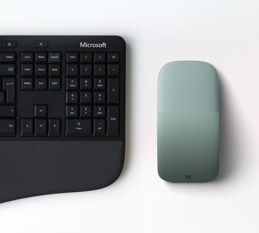 Microsoft Arc Mouse neben einem Microsoft Ergonomic Keyboard.