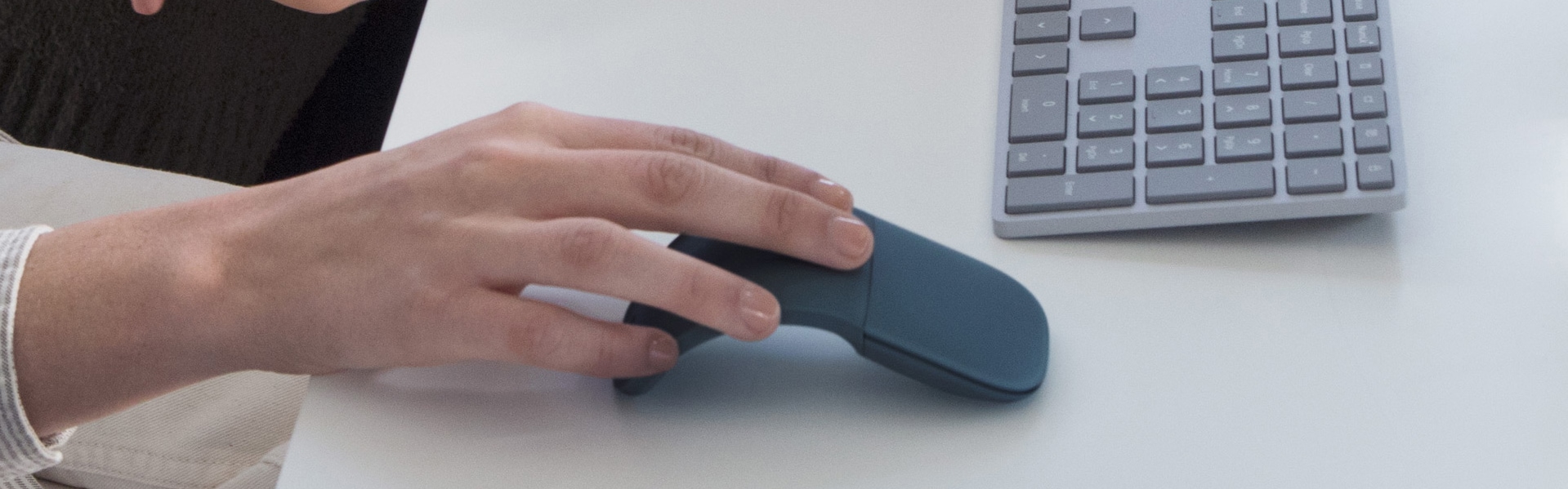 شخص يستخدم ماوس Surface Arc Mouse باللون الأزرق الكوبالت