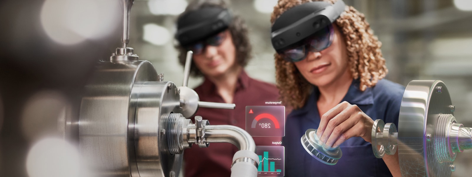 One woman uses a HoloLens device at work, while another female coworker observes.