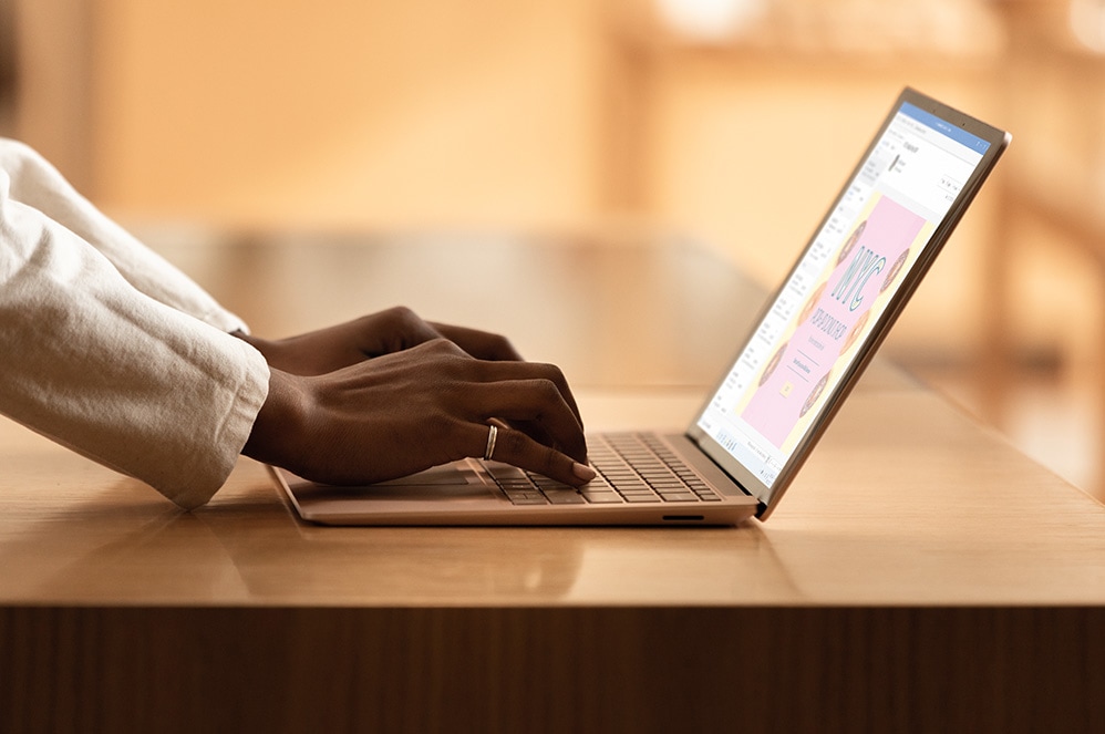 A woman works on a PowerPoint presentation with her Surface Laptop 3 for Business in sandstone colour