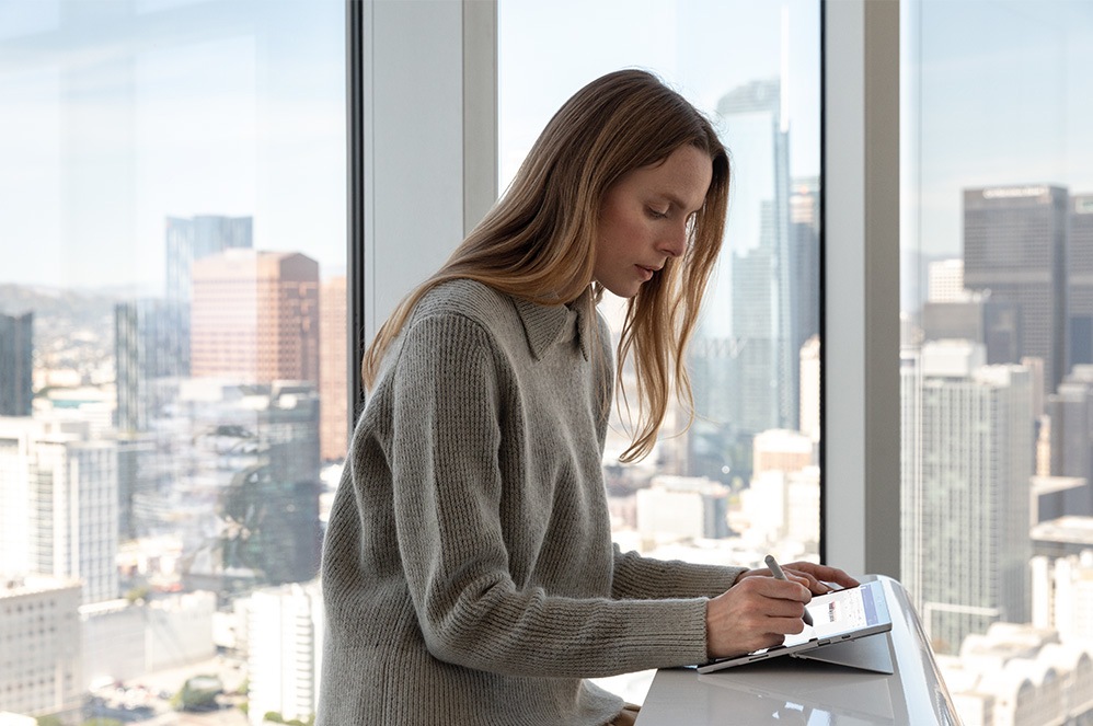 Woman using Surface pen on Surface device screen at a desk