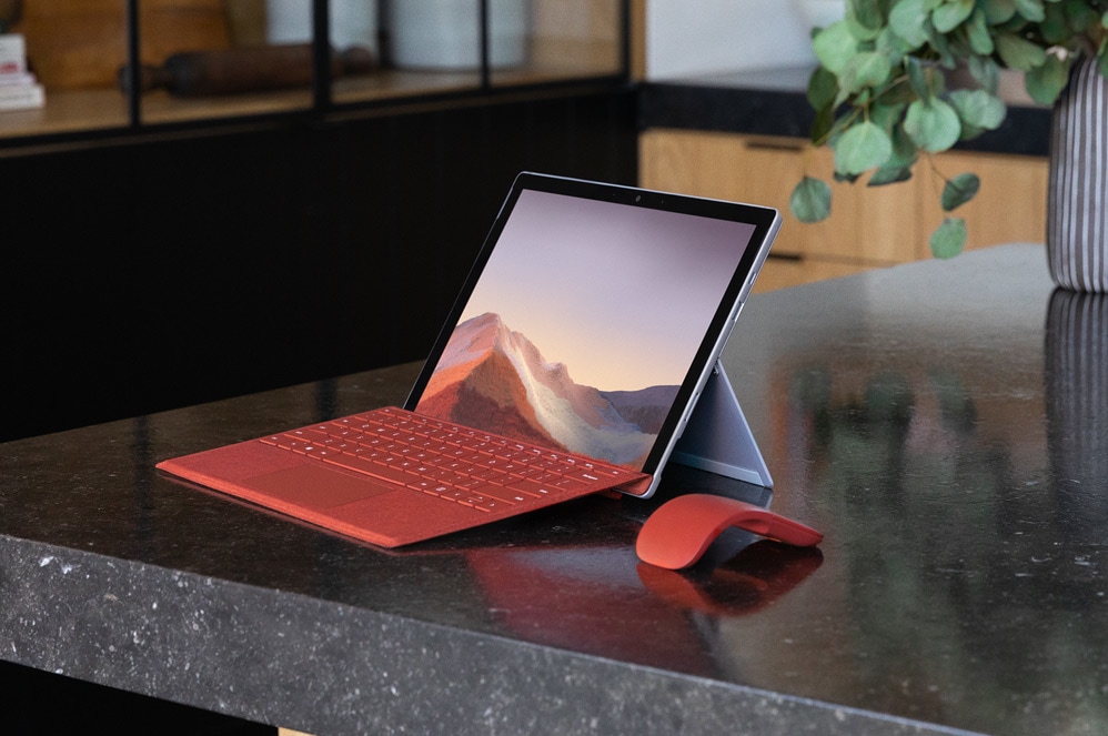 Surface Pro 7  på ett bord med Type Cover och Arc Mouse
