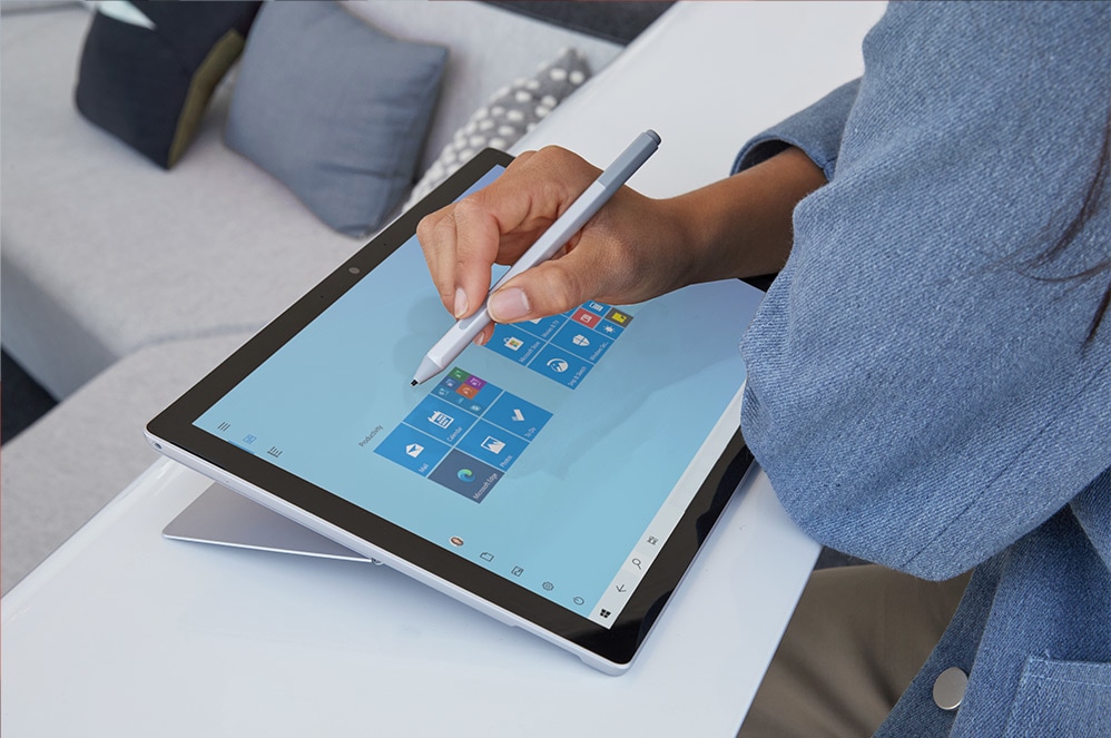 Une femme touche l'écran de son ordinateur portable tactile Surface Pro 7