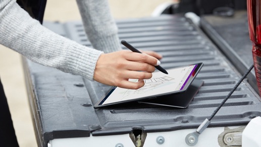 A person works on their Surface Pro X outside