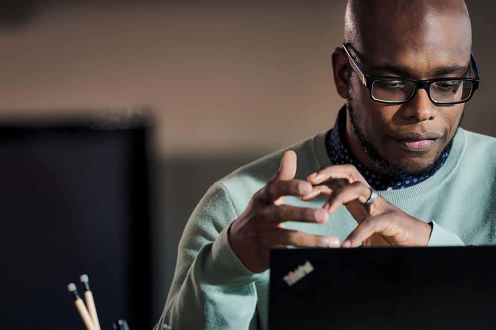 En manlig medarbetare som arbetar på distans från sitt hemmakontor på en Lenovo ThinkPad-enhet