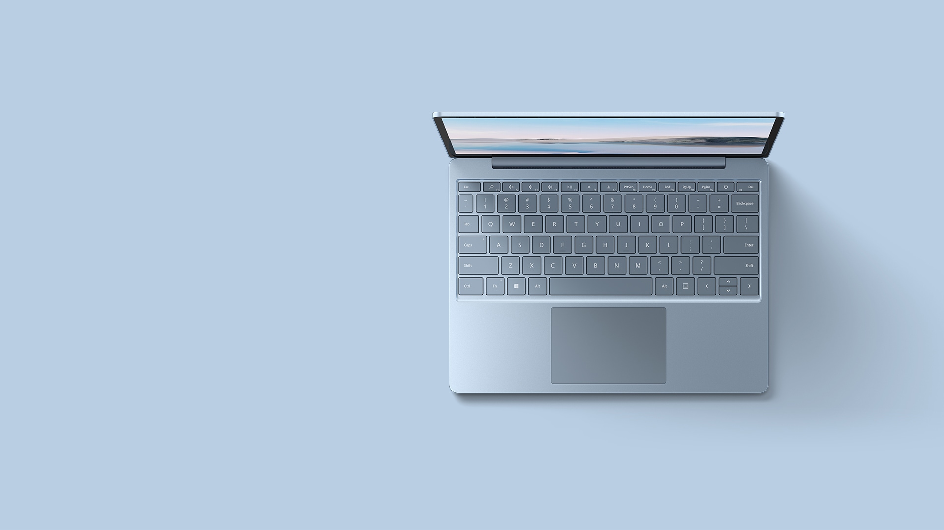 An aerial view of the ice blue Surface Laptop Go resting upon a matching background.