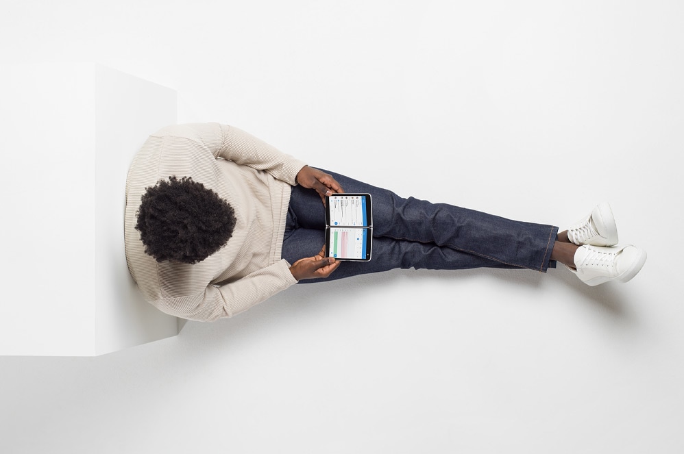 A person reclines holding Surface Duo like a book