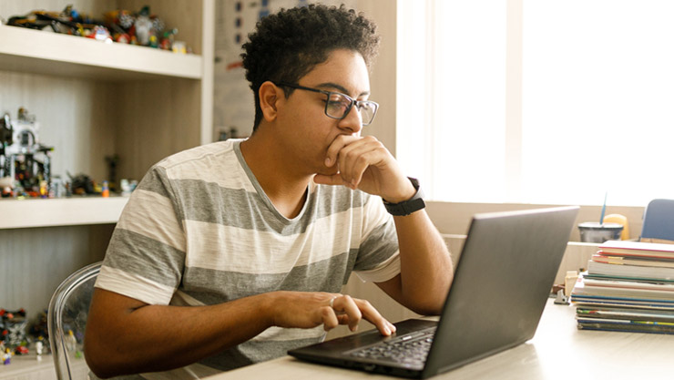 A young man sitting at his desk while interacting with the touchpad on his Windows 10 PC