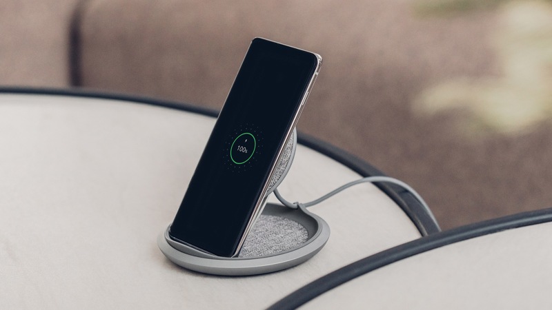 Angled view of Moshi Lounge Q Wireless Charger with charged phone.