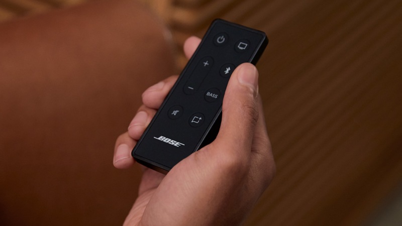 A man holding the controller for the BOSE TV Speaker