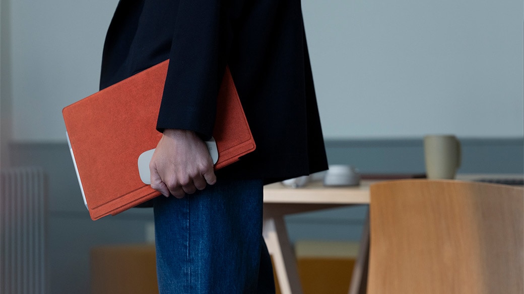 Person carrying Surface Pro 7 with Surface Type Cover closed and Surface Mouse
