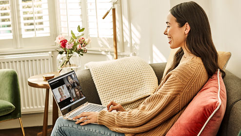 Woman sitting on couch, video conferencing with her laptop