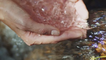 Handen houden water uit een bron eronder vast