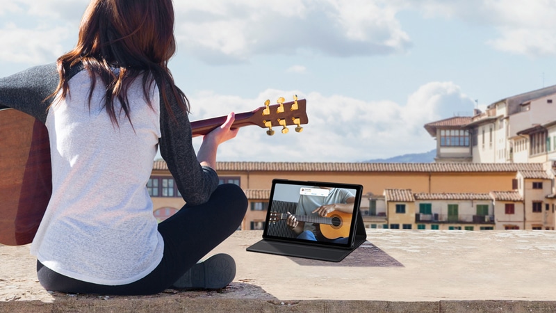 Girl playing the guitar with someone else through a video call on the Samsung Galaxy Tab A7