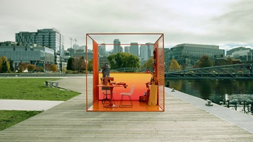 A small, futuristic, and colorful office space in the middle of a park outside a large city