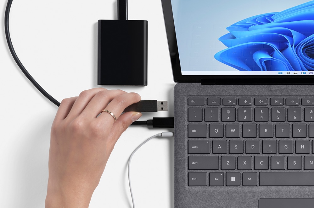 A user connects multiple cables to the Surface Laptop 4.