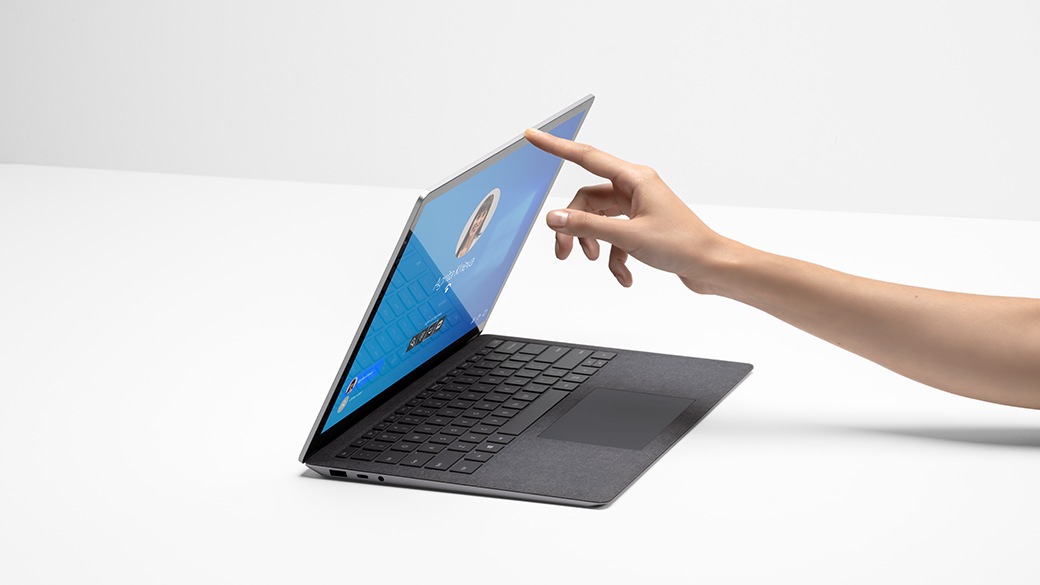 A person’s hand with finger lifting the lid of Surface Laptop 4 for Business.