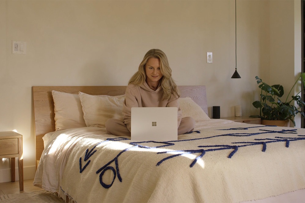 Una usuaria, sentada en un sofá, escribe en su Surface Laptop 4.