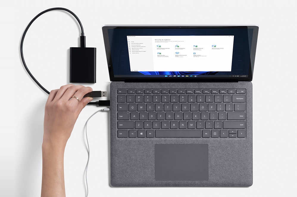 Se muestra la mano de una persona que conecta una unidad de disco externa a Surface Laptop 4