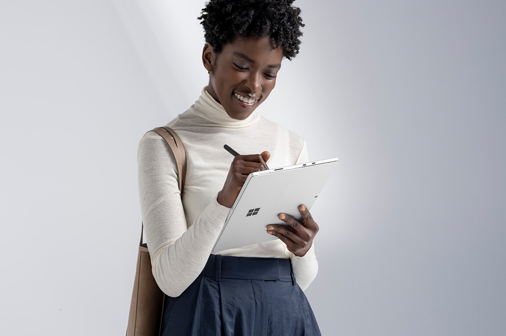Eine Person hält Surface Slim Pen 2 und schreibt auf einem Surface-Gerät.