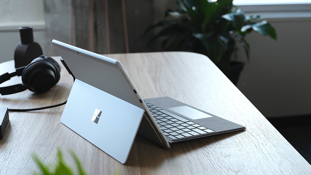 Un persona sentada en un escritorio que trabaja con Surface Pro X para empresas.
