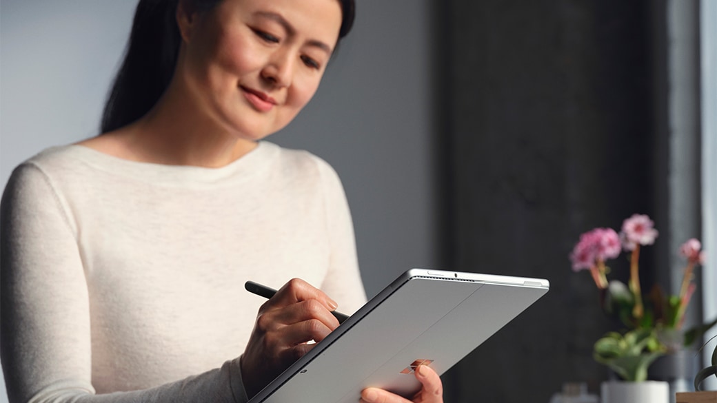 Een persoon met een koptelefoon op zit aan een tafel met een Surface Pro 8 voor zakelijk gebruik.