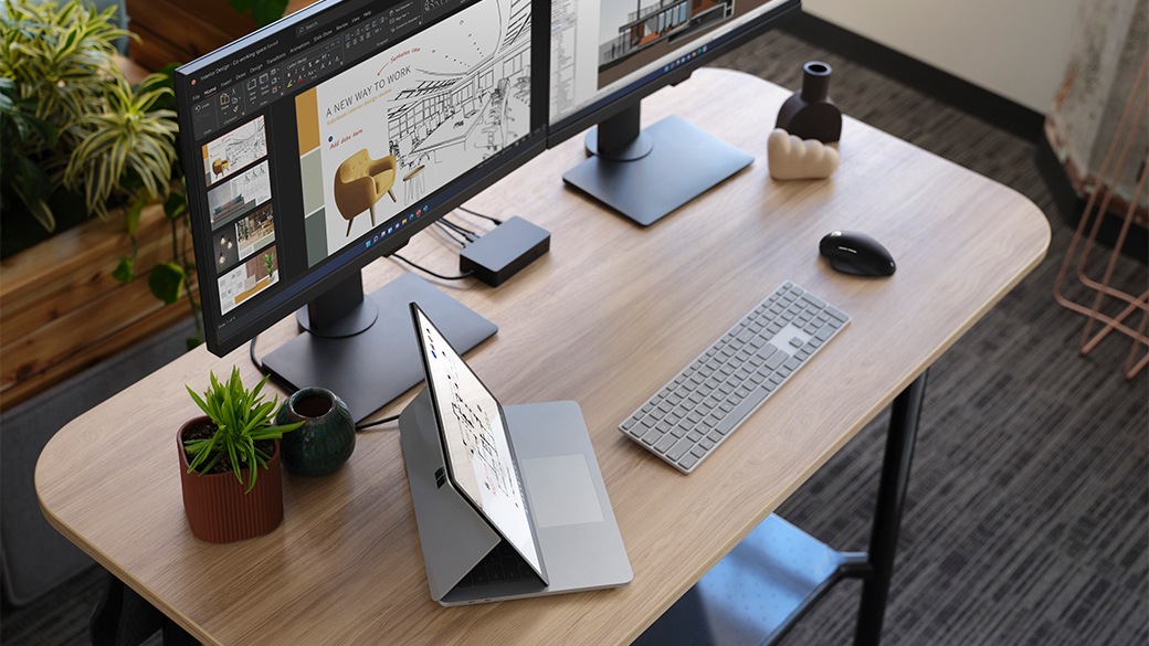 A person seated at a table working with Surface Laptop Studio for Business.