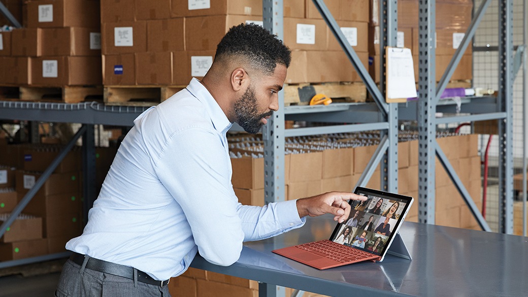 Een persoon staat aan een bureau en werkt met Surface Pro 7+ voor zakelijk gebruik.