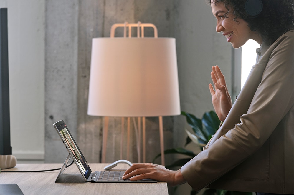 Une personne se tenant devant un bureau et travaillant avec Surface Pro X pour les entreprises.