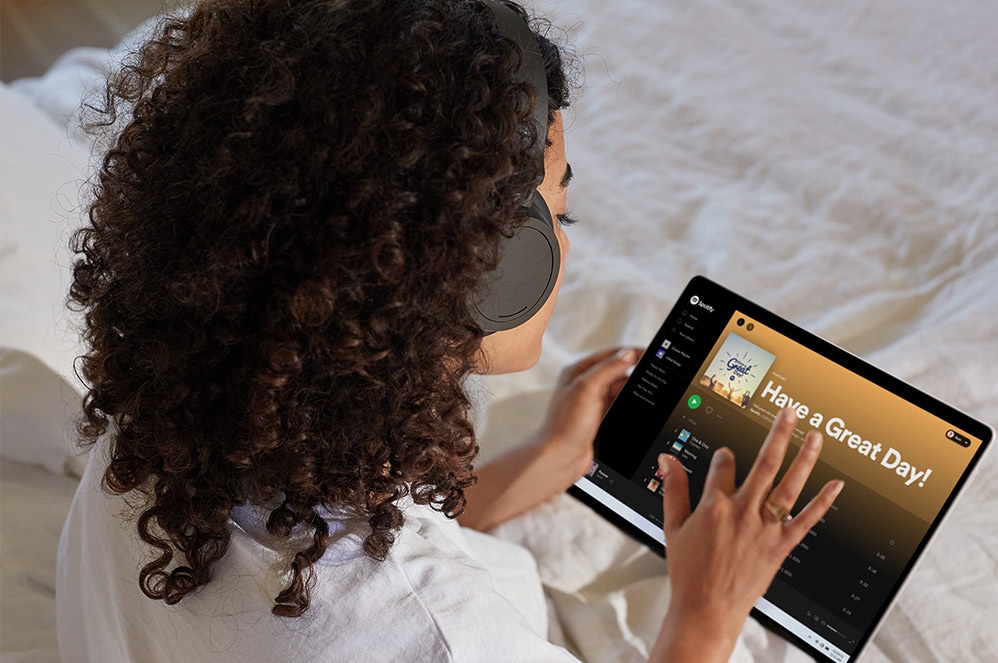 Surface Pro X utilisée sous forme de tablette pour écouter Spotify.