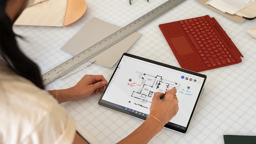 Una persona trabaja en un escritorio con Surface Pro X para empresas sobre una mesada.