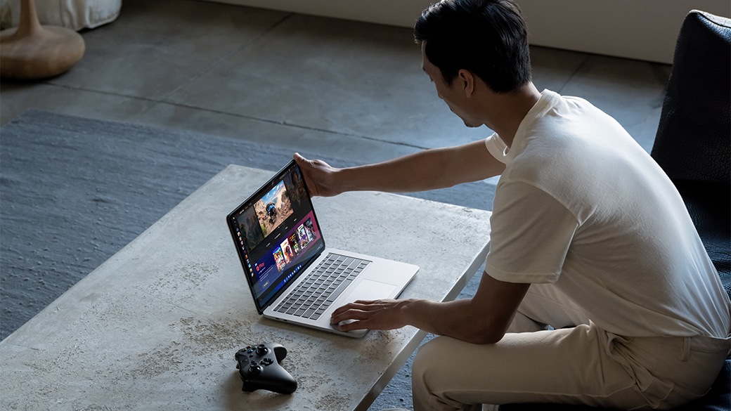 A person's hand holding the edge of the Surface Laptop Studio for Business screen.