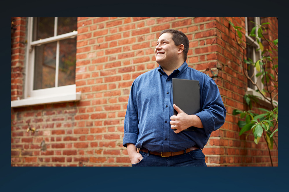 A man standing outside holding a laptop